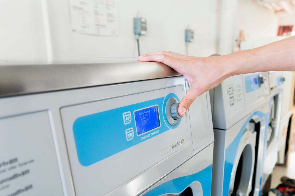 En person sätter på en tvättmaskin med tummen. 